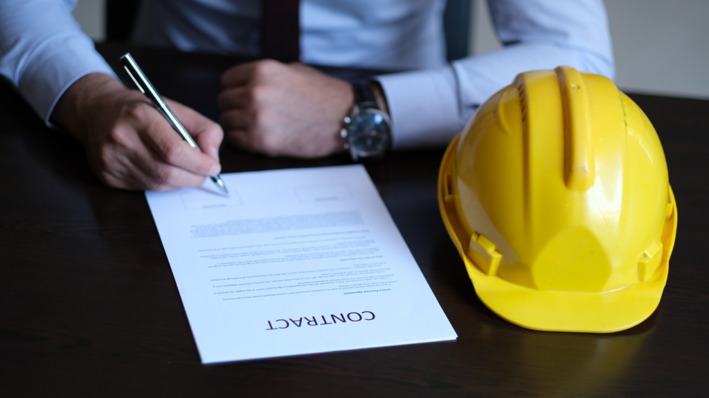 Man signing a contract with a construction hat on the table