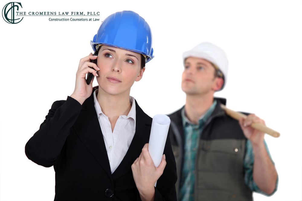 A woman in a blue hard hat, holding blueprints and talking on a phone, stands in the foreground. A man in a white hard hat, holding a tool, is blurred in the background. The logo of "The Cromeens Law Firm, PLLC" is in the top left corner.