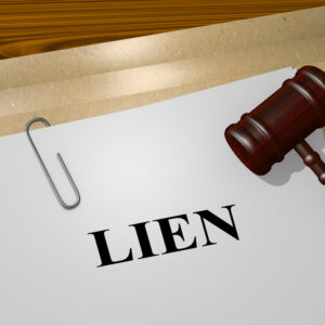 A stack of papers with the word 'Lien' on the top page, next to a judge's gavel on a wooden desk.