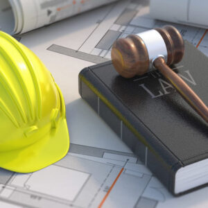 hardhat and gavel on notebook on top of construction plans