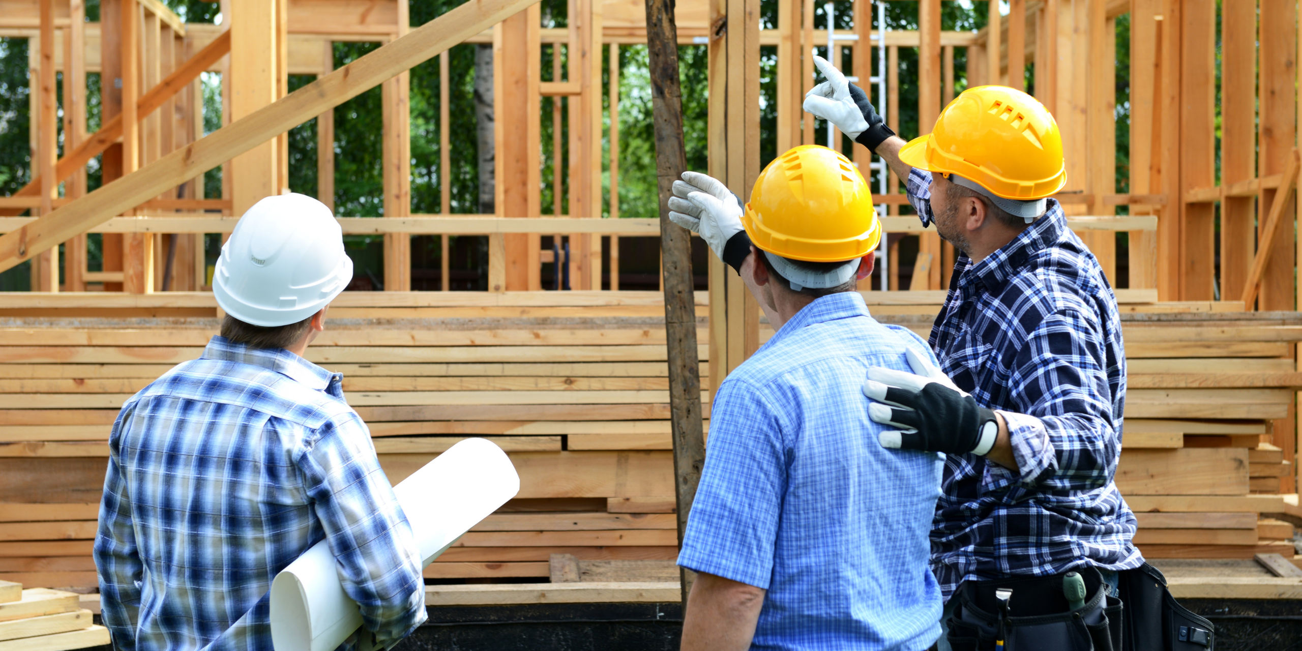Residential contractors reviewing building plans at a wood frame home construction site